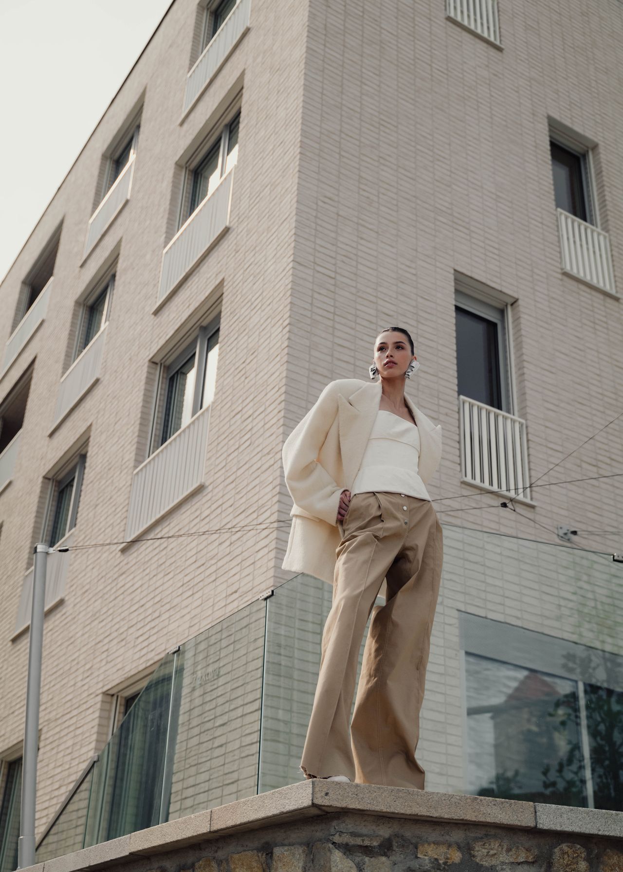 Fashion editorial woman in cream knit outfit standing on building rooftop — Thomas Habr fashion photographer