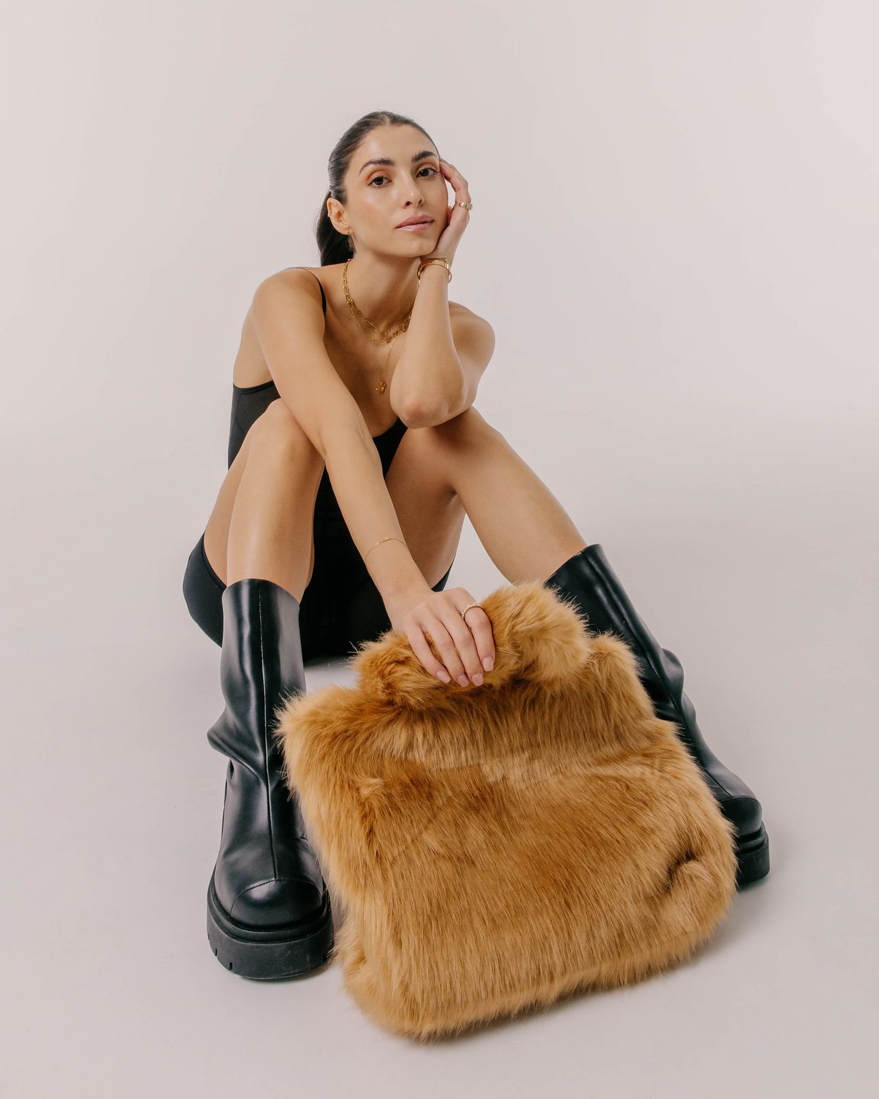 Luxury fashion editorial woman seated with fur bag and knee-high boots — Thomas Habr photographer