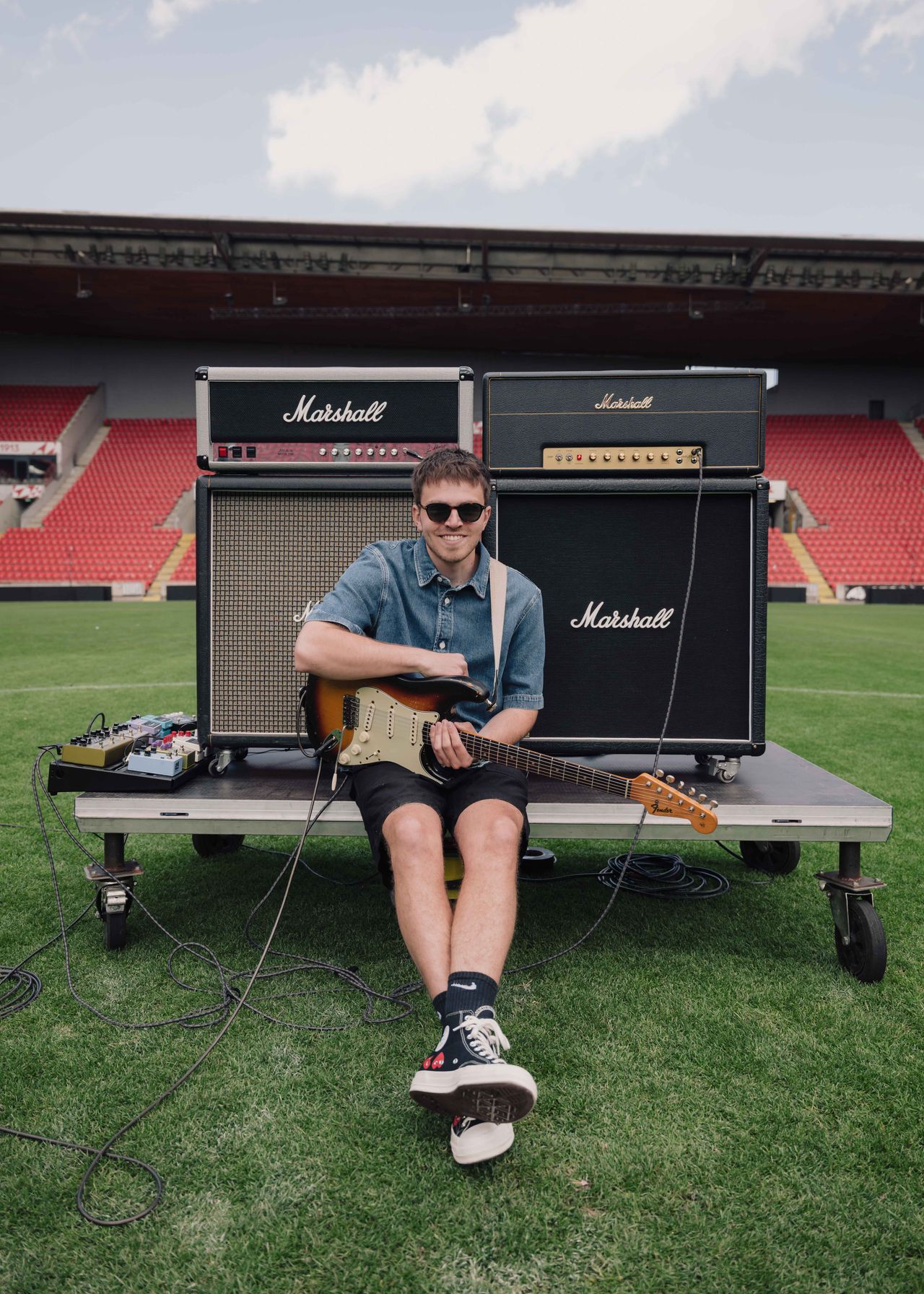 Music artist portrait sitting on stadium stage with Marshall amplifiers and guitar — Thomas Habr music photographer